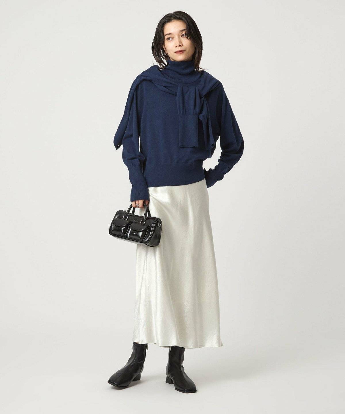 ネイビーのニットにベージュのスカートを合わせた女性