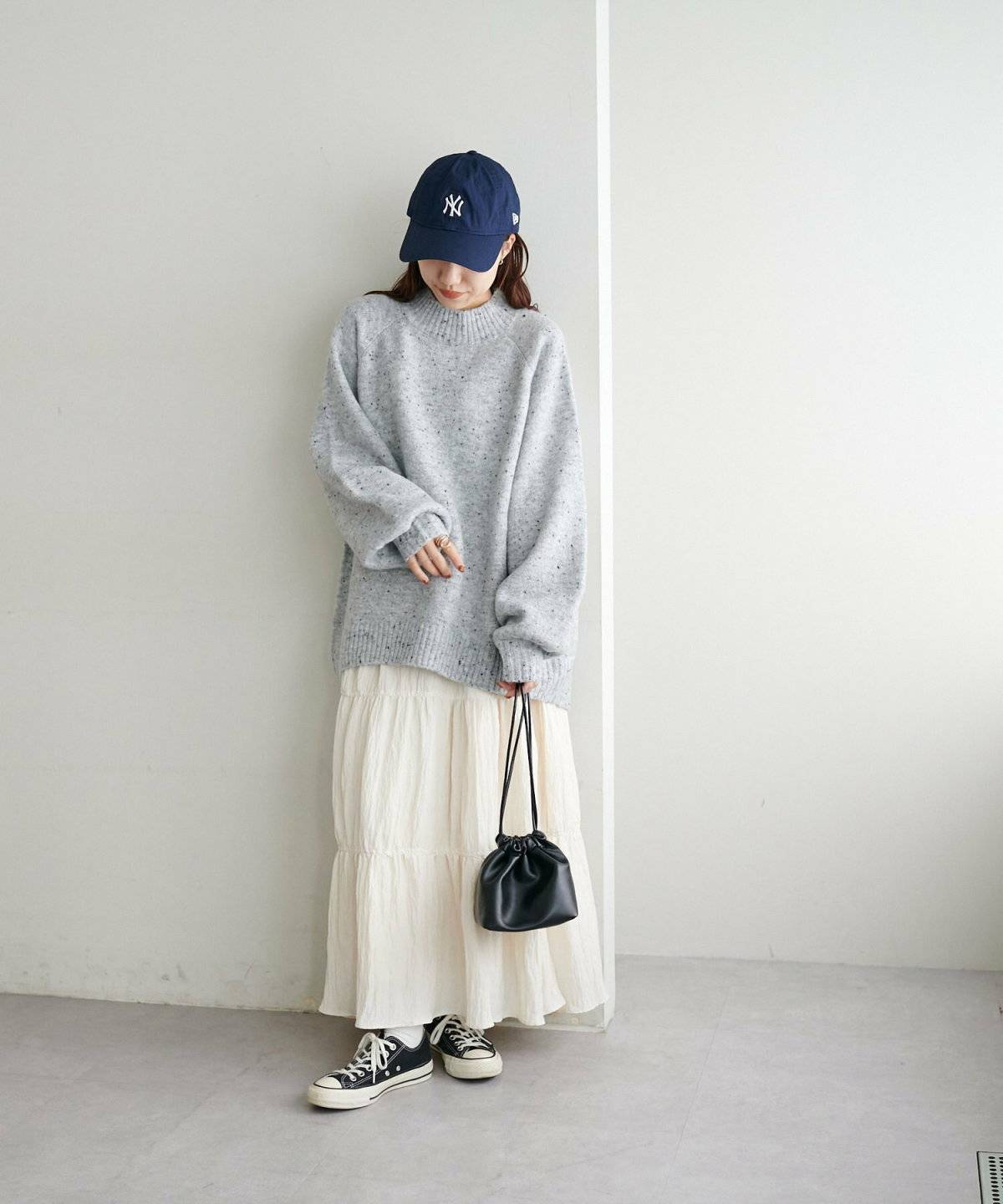 グレーのニットに白スカートを合わせた女性