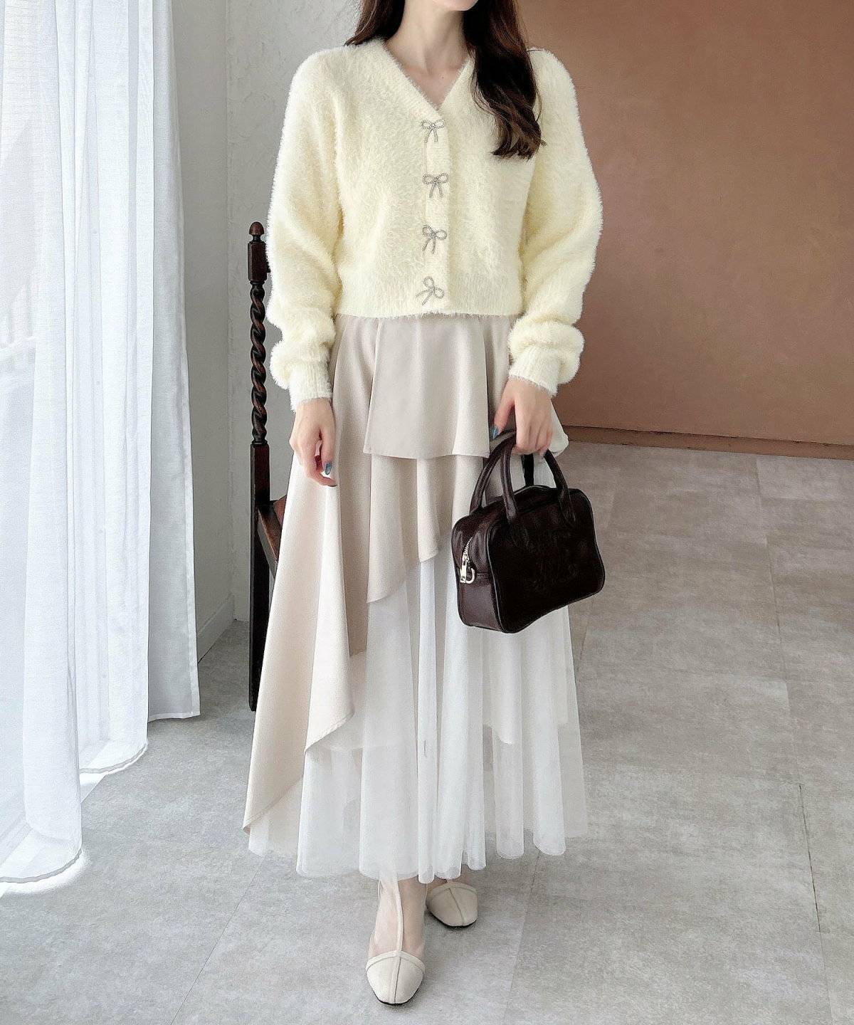 イエローのカーディガンに白スカートを合わせた女性