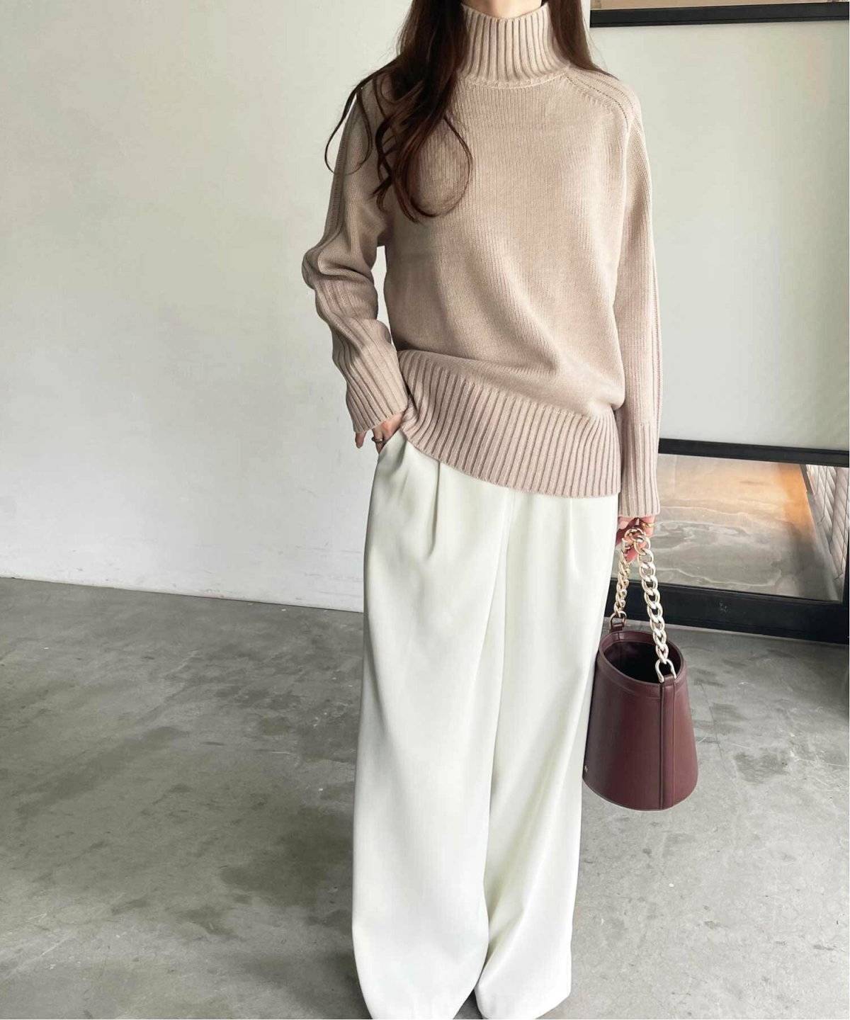 ベージュのニットに白のパンツを合わせた女性