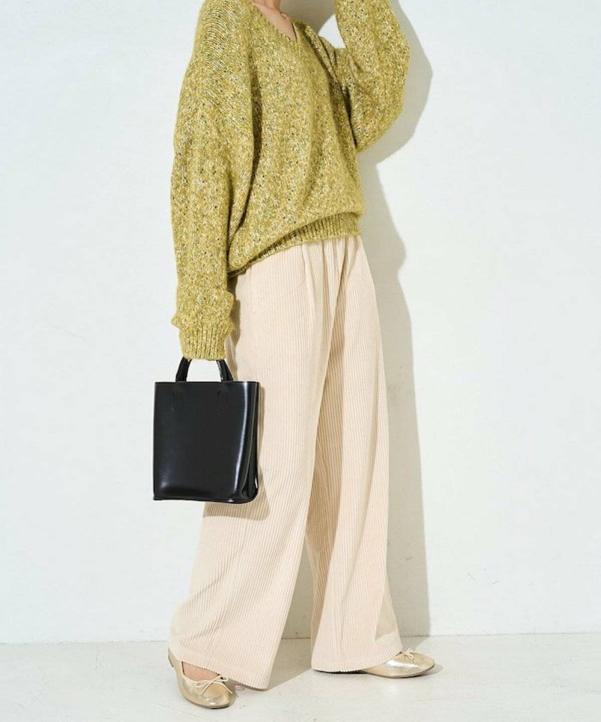 グリーンのニットに白パンツを合わせた女性