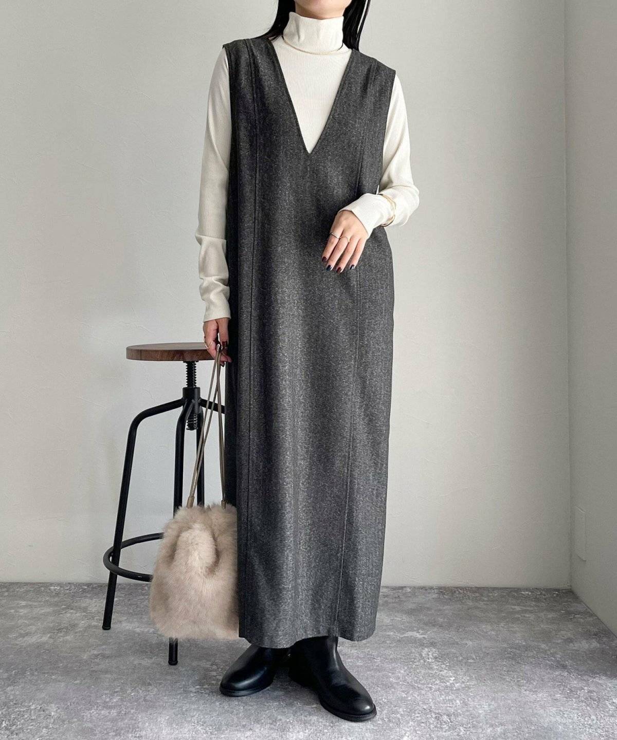 白ニットにグレーのジャンパースカートを重ねた女性