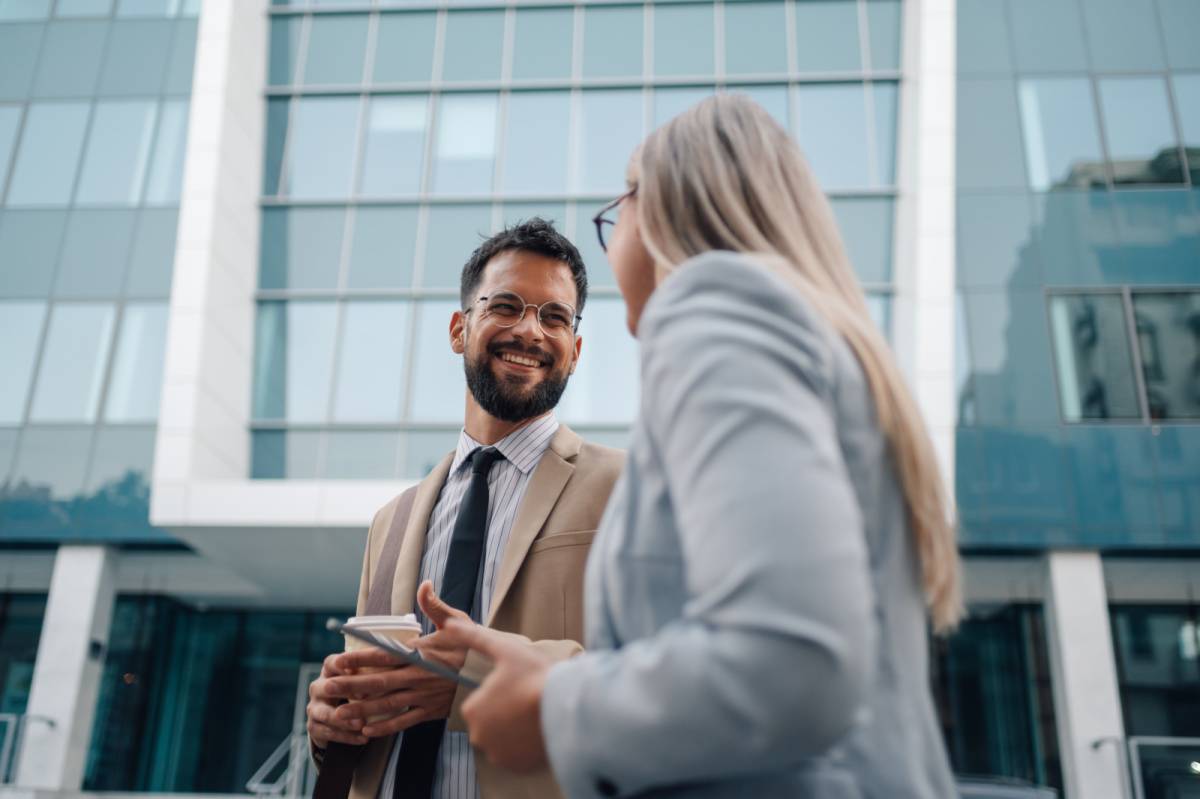 外を歩きながら同僚と話す男性