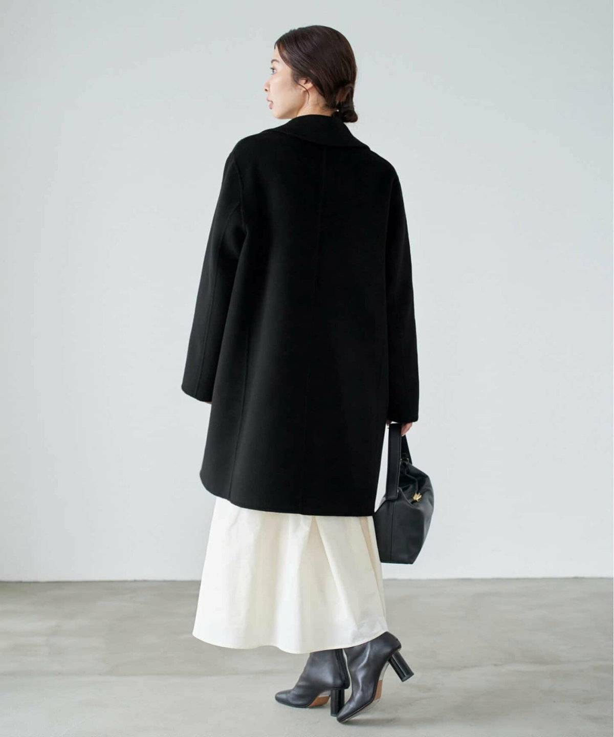 黒アウターにベージュのスカートを合わせた女性