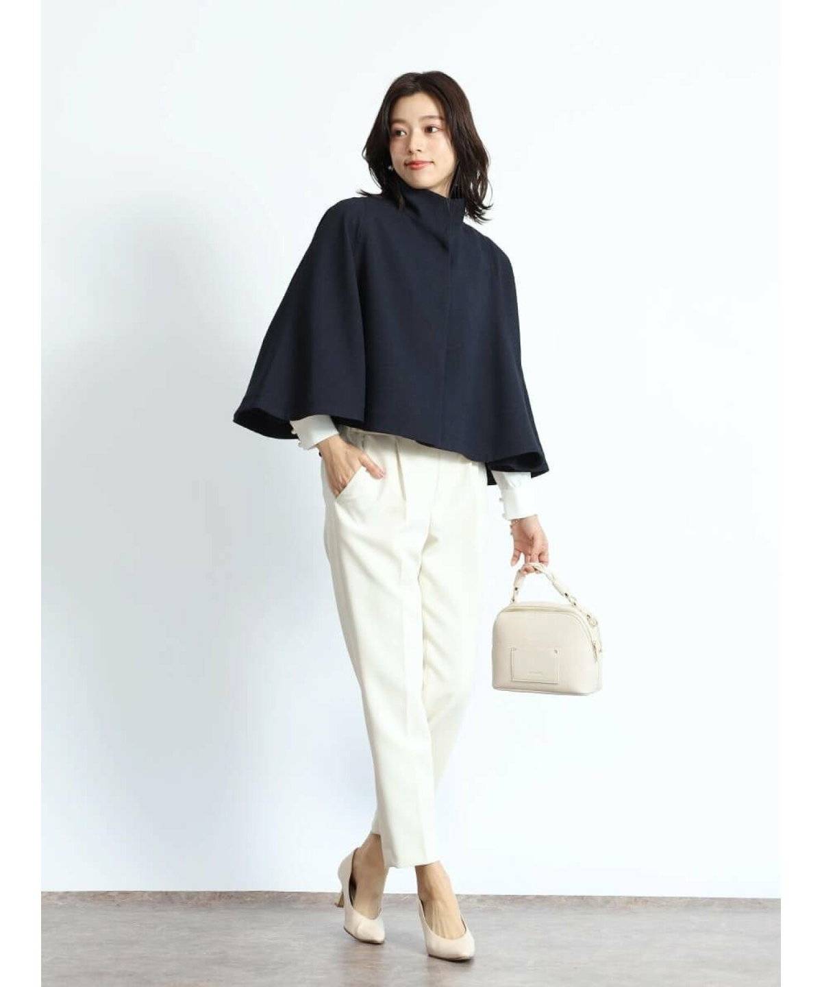 ネイビーのコートに白パンツを合わせた女性