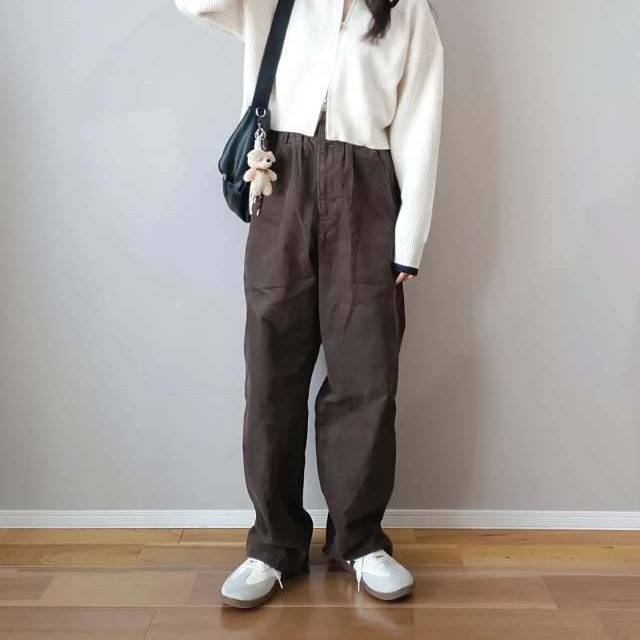 白カーディガンにブラウンパンツを合わせた女性