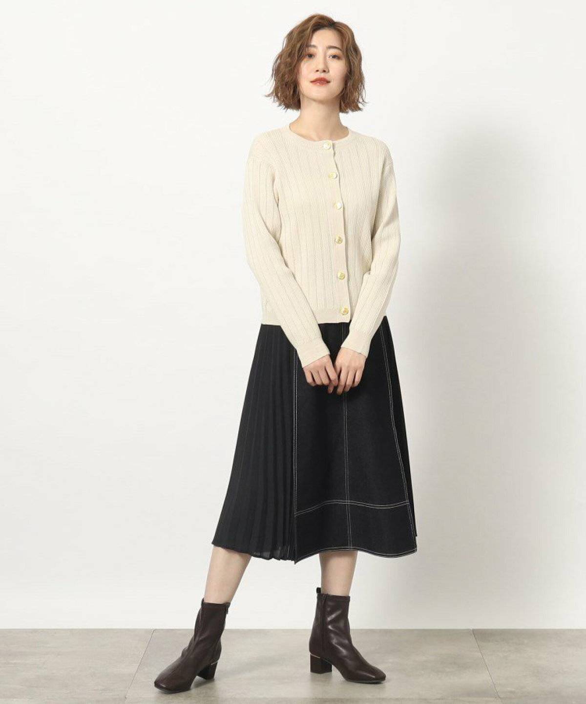 ベージュのカーディガンにデニムスカートを合わせた女性