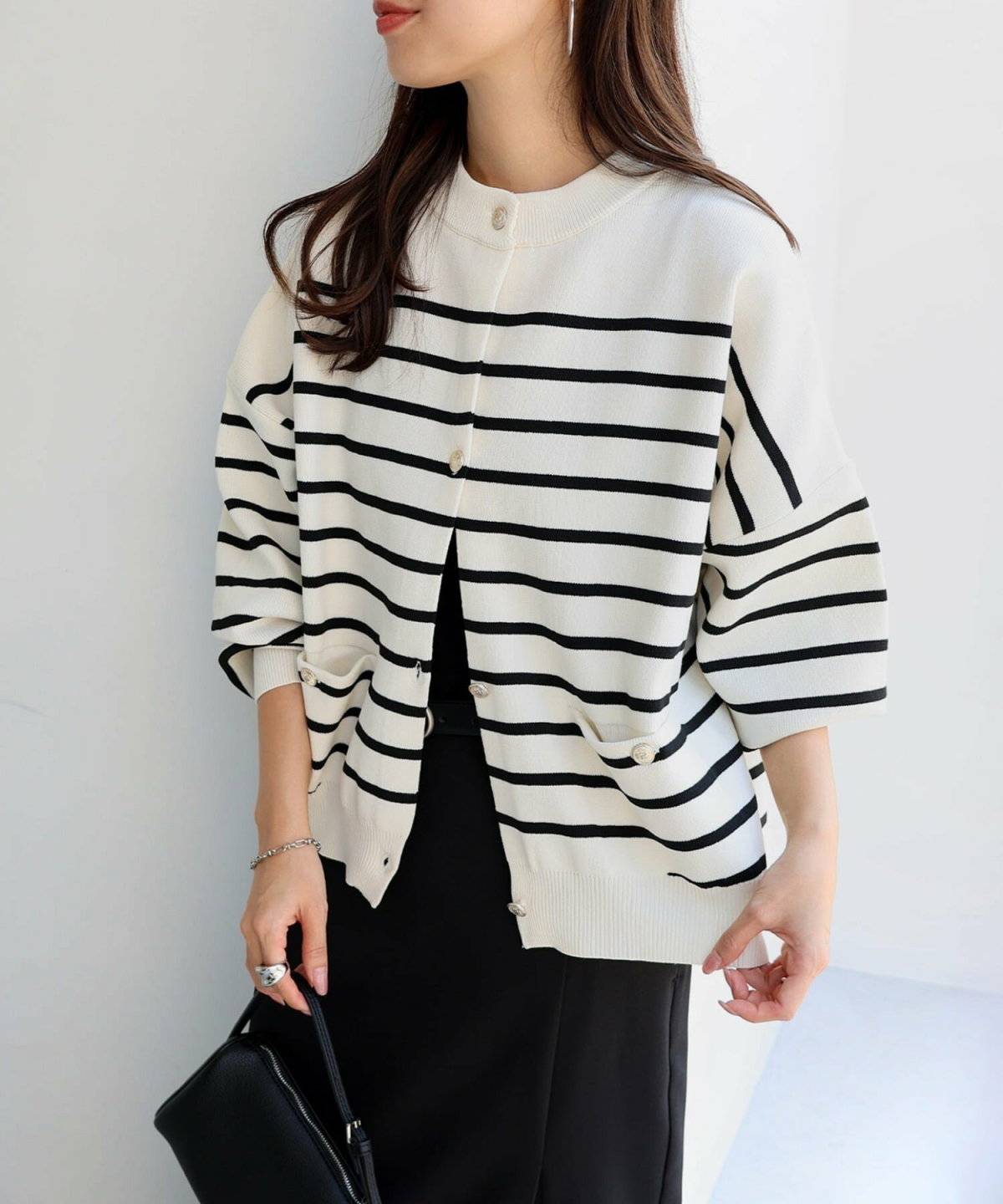 黒のサロペットにボーダー柄カーディガンを羽織った女性