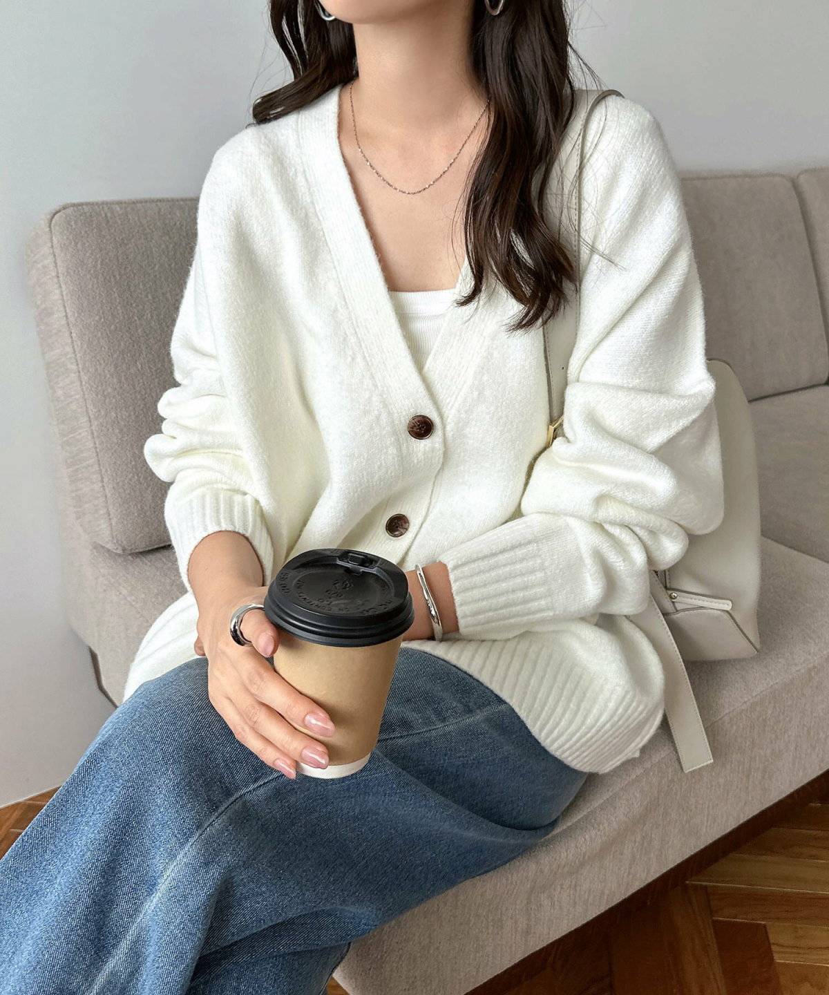 白のカーディガンにデニムを合わせた女性