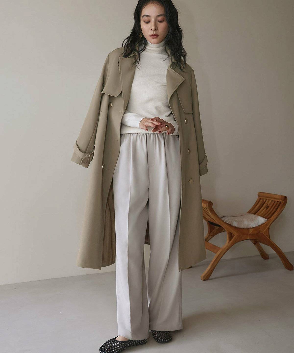 ホワイトコーデの上にベージュのトレンチコートを羽織った女性