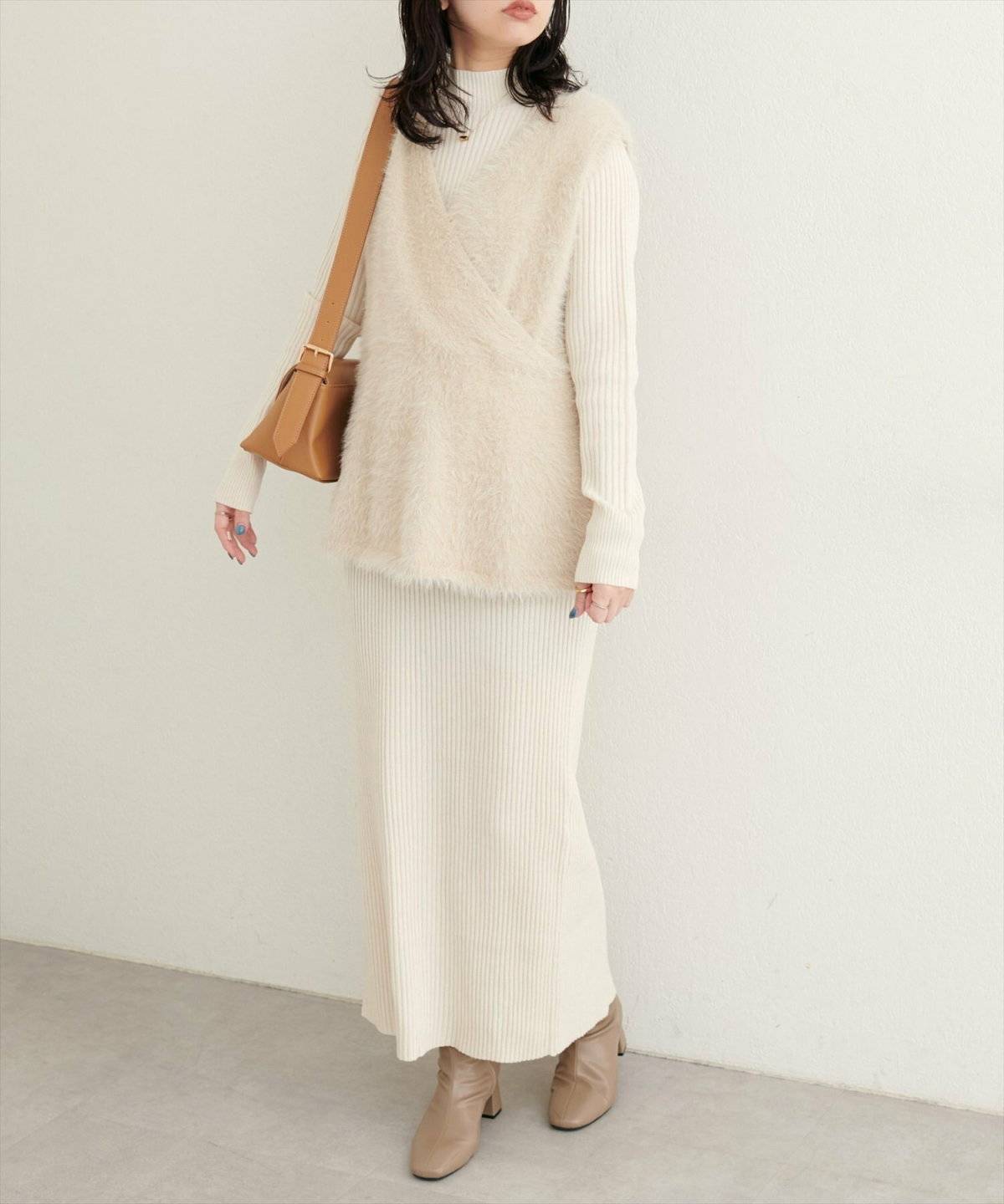 白ワンピースにベージュのベストを重ねた女性