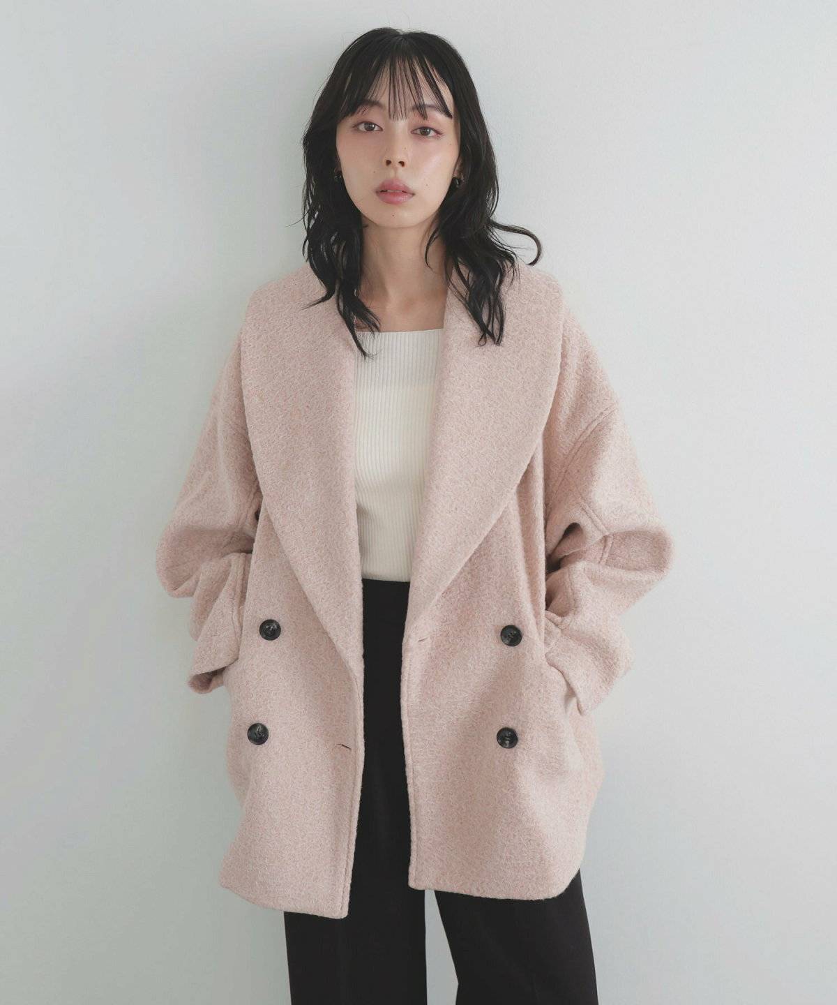 モノトーンコーデにピンクのジャケットを羽織った女性