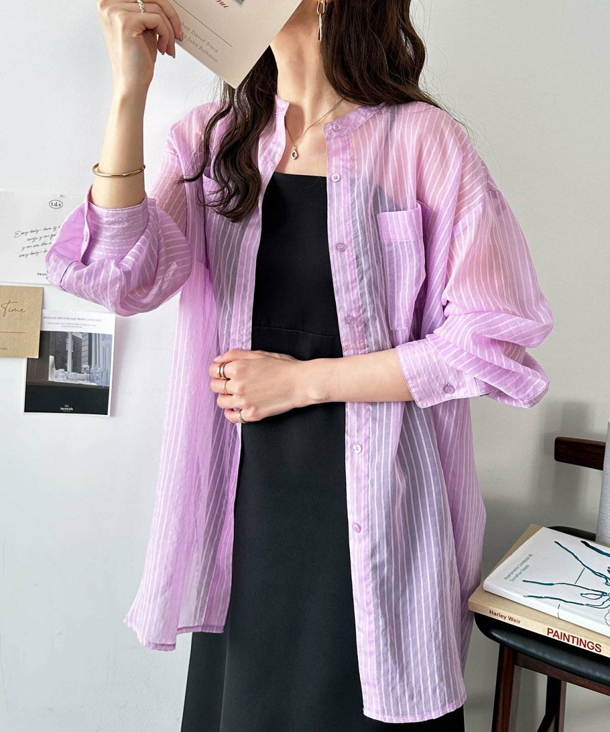 ピンクのシャツに黒ワンピースを合わせた女性