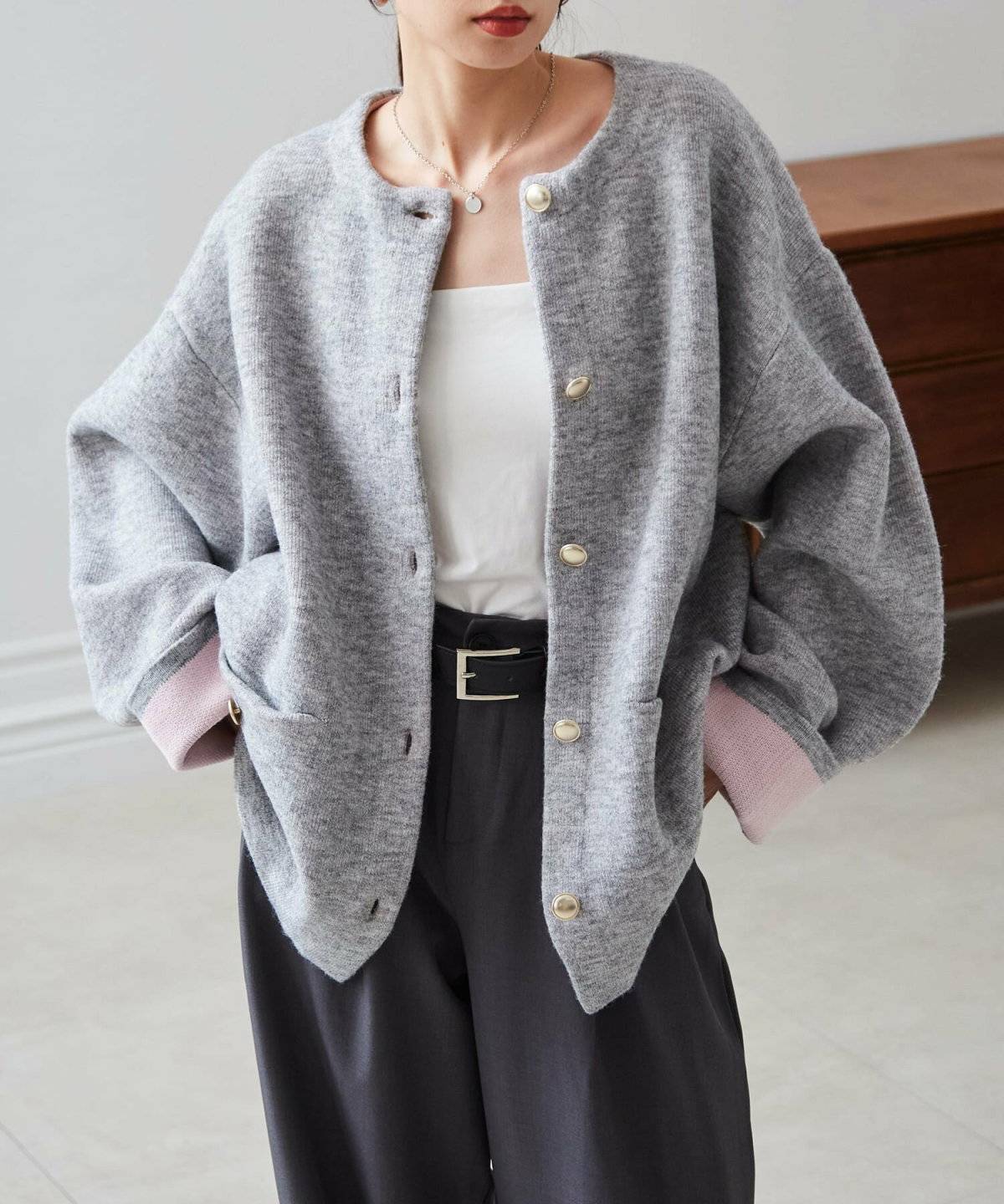 グレーのカーディガンに黒パンツを合わせた女性