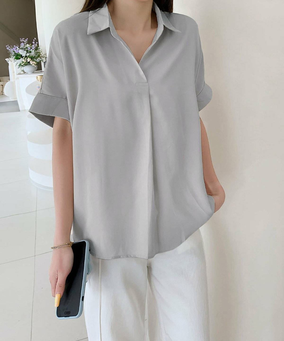 グレーのブラウスに白パンツを合わせた女性