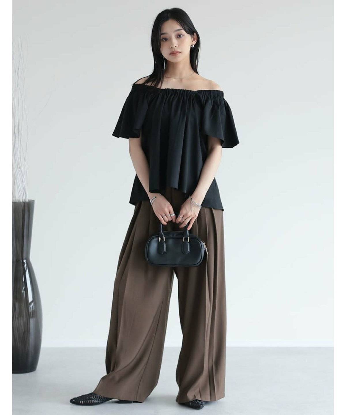 黒ブラウスにパンツを合わせた女性