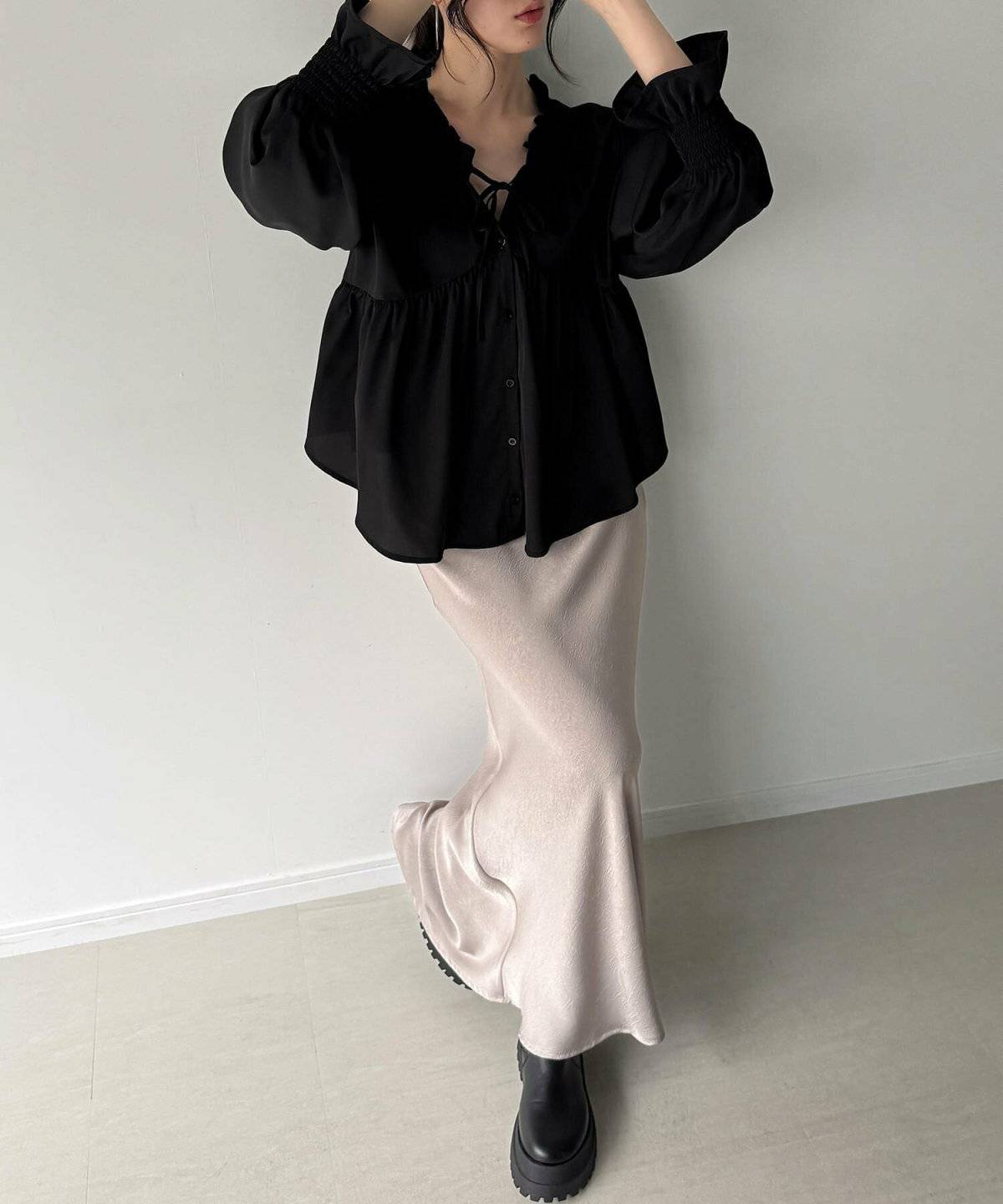 黒ブラウスにベージュのスカートを合わせた女性
