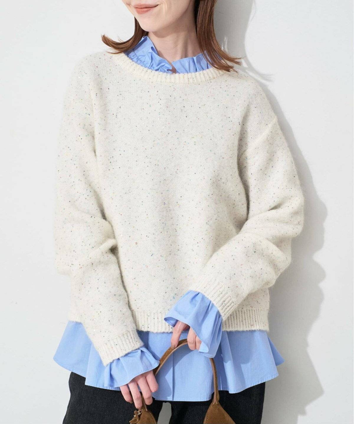 ブラウスにニットを重ねてデニムを穿いた女性