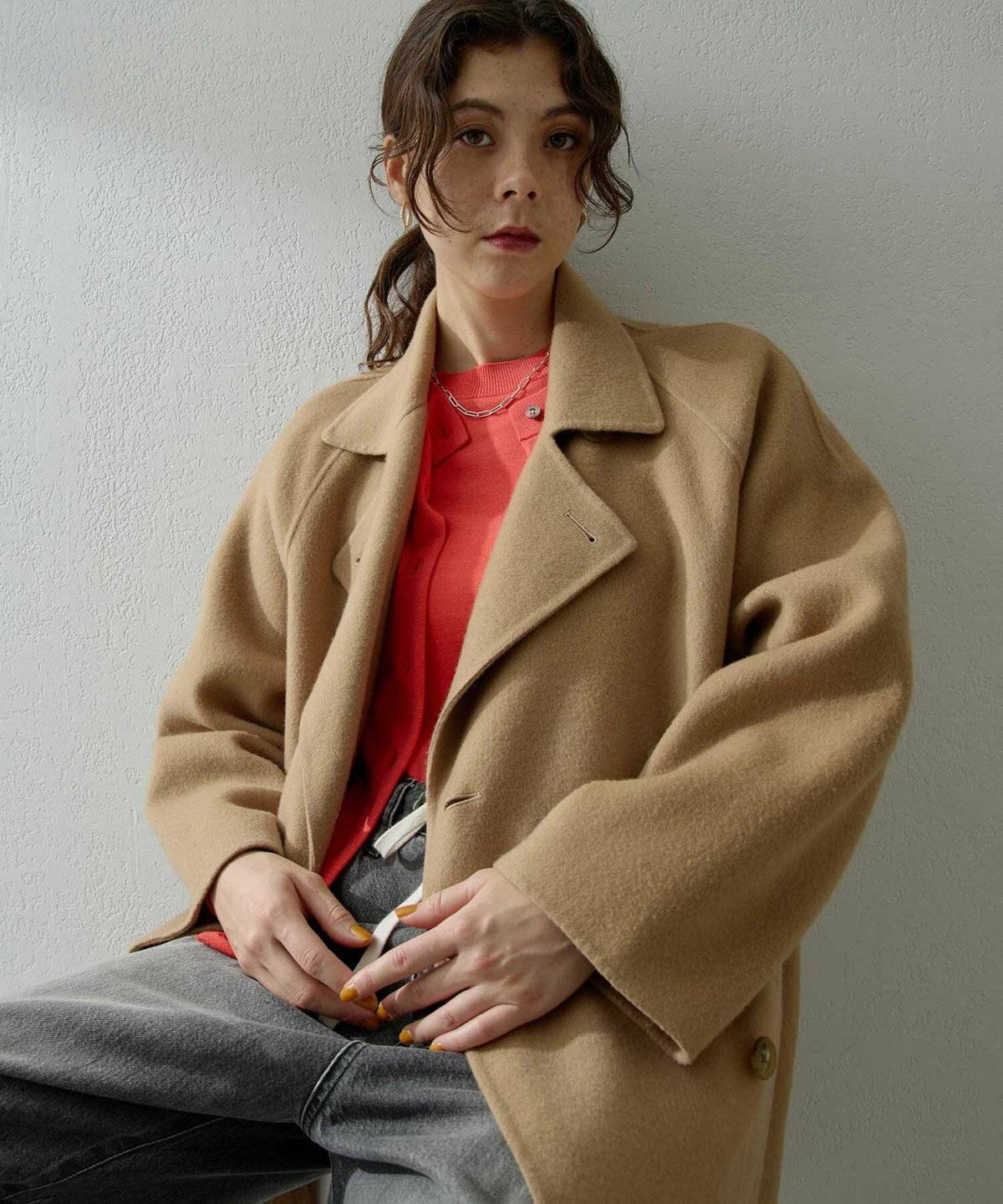 キャメルコート✕赤ニットの女性