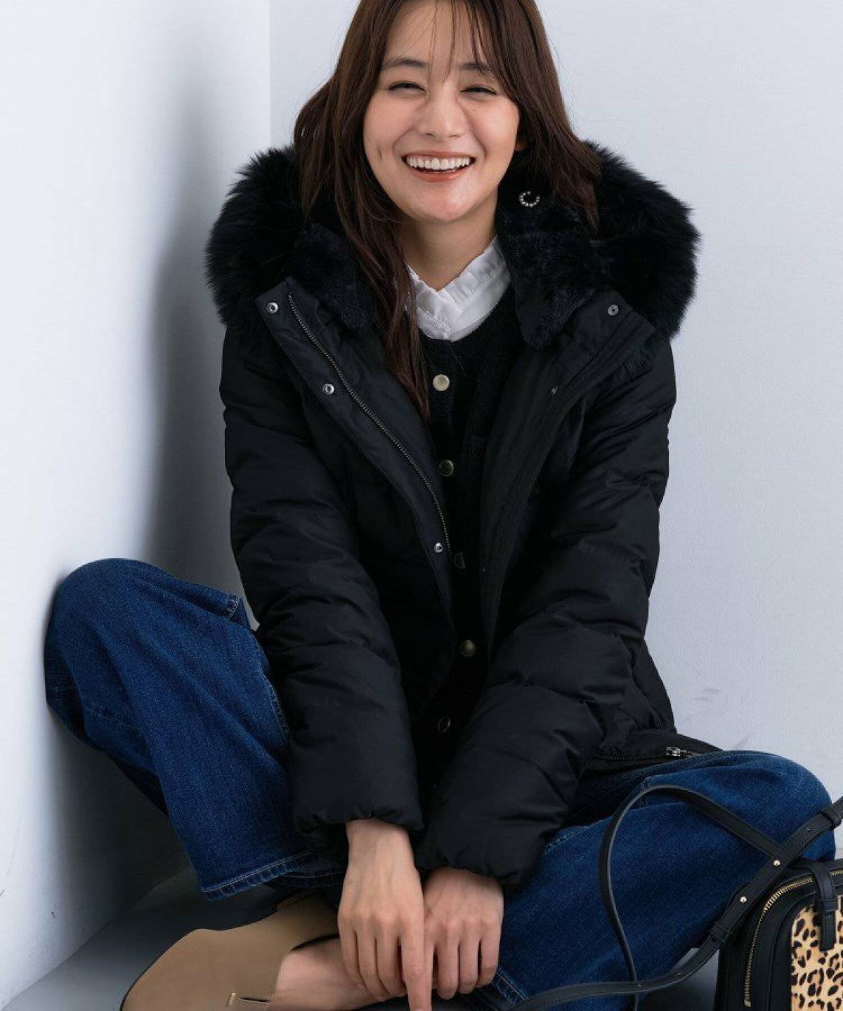 黒トップスに黒ダウンを羽織ってデニムを合わせた女性