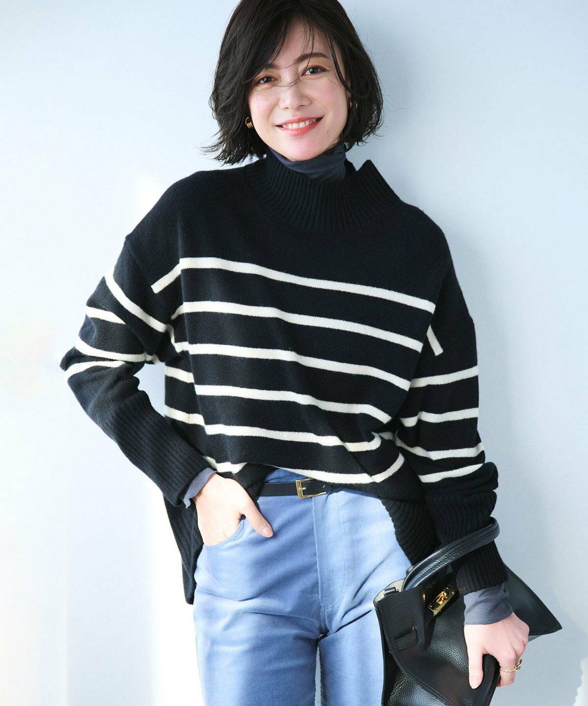 ボーダー柄ニットにシャツを重ねてデニムを履いた女性