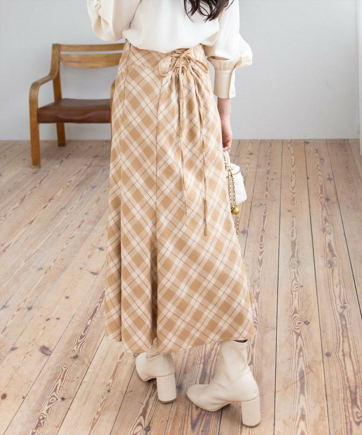 ベージュのシャツにチェック柄スカートを合わせた女性