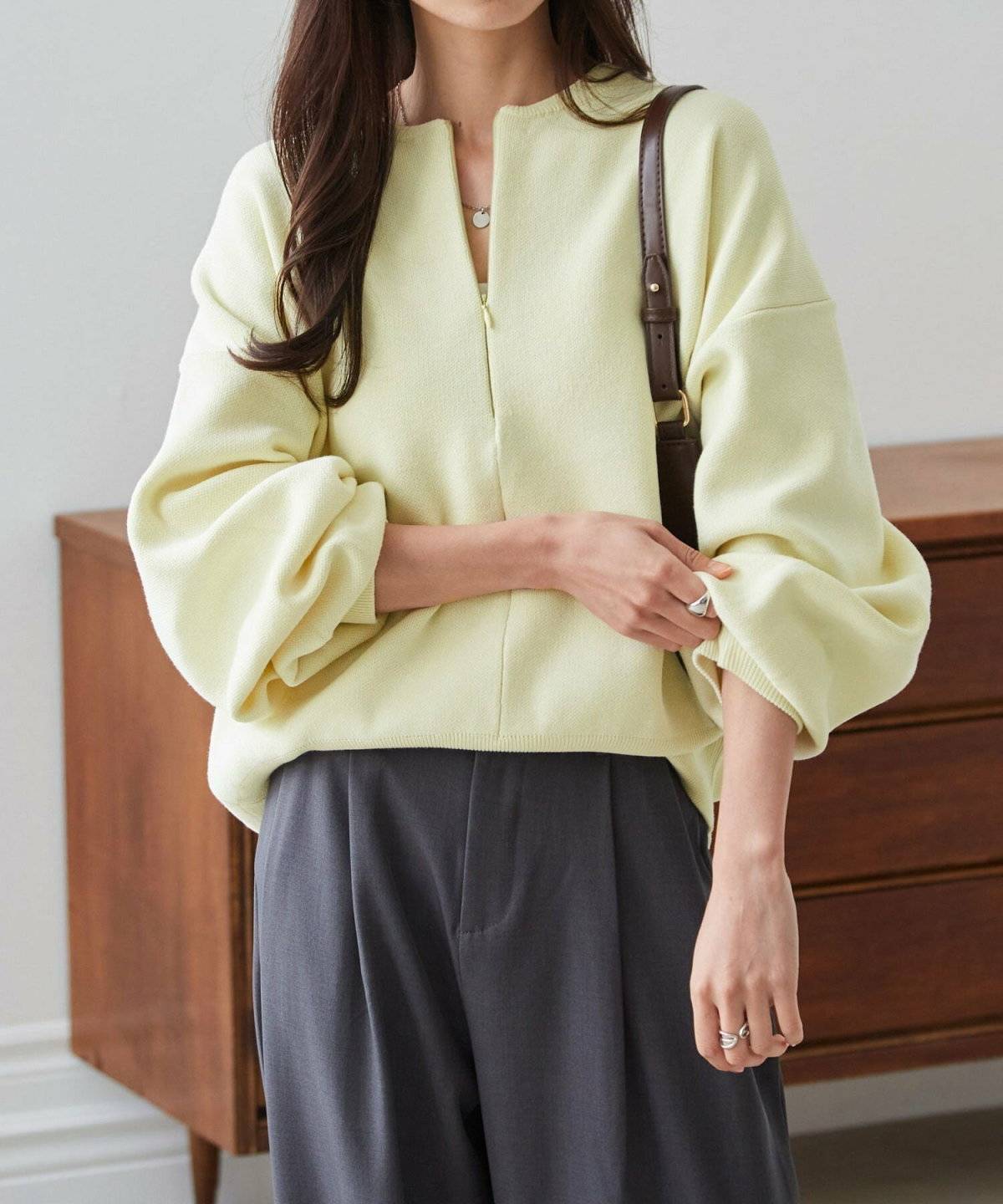 イエローニットにグレーパンツを合わせた女性