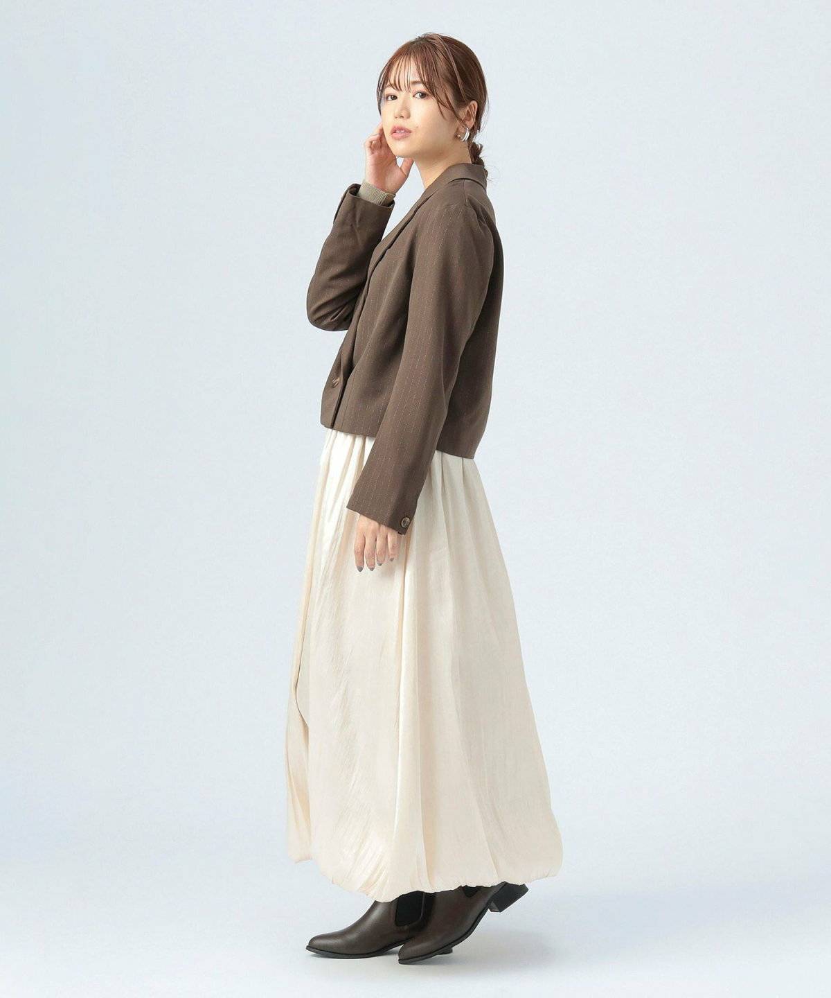 ジャケットを羽織って白スカートを合わせた女性