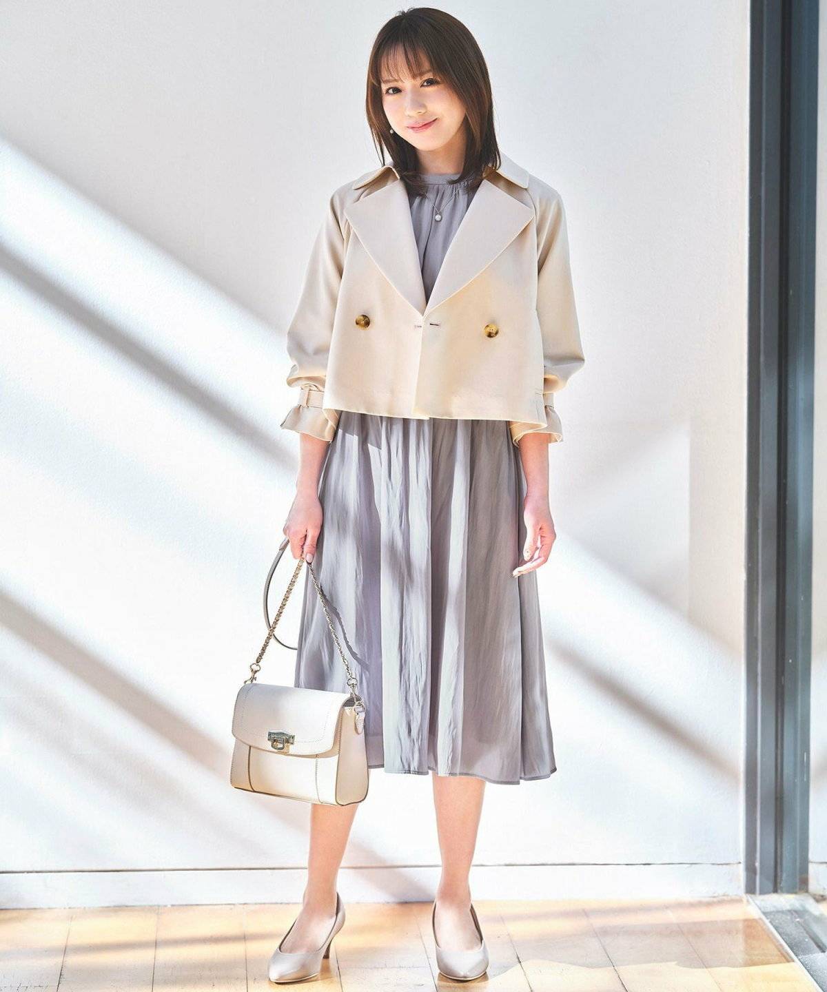 ベージュのトレンチにワンピースを合わせた女性