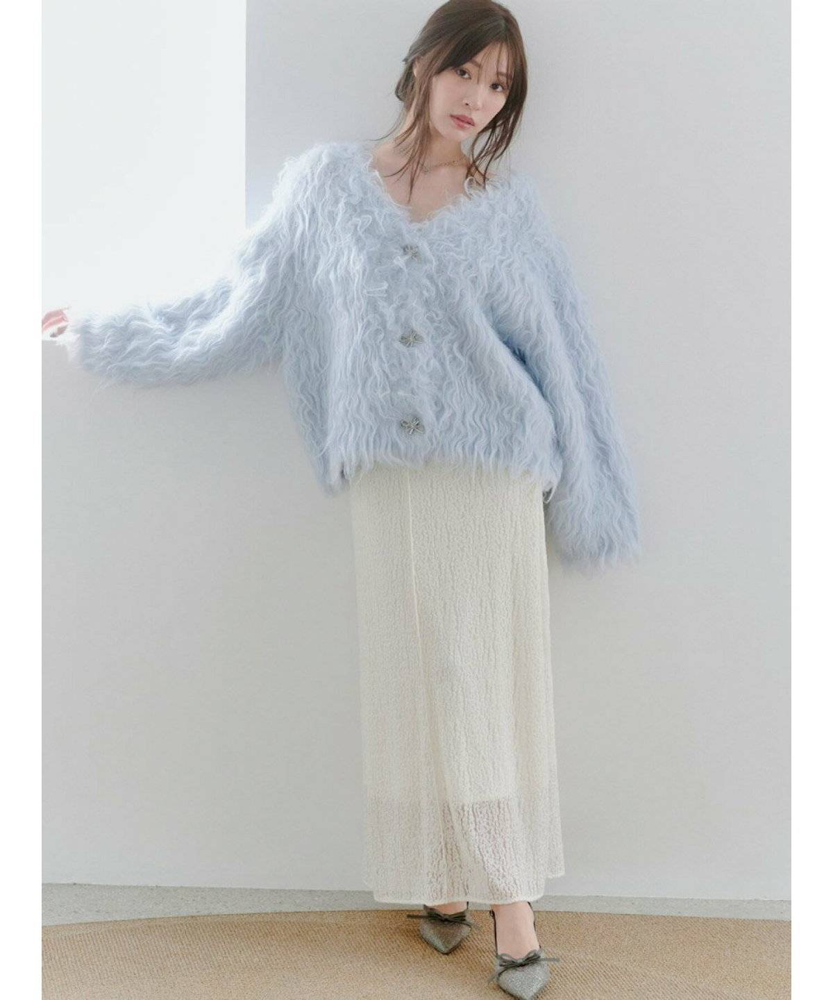 ブルーのカーディガンに白スカートを合わせた女性