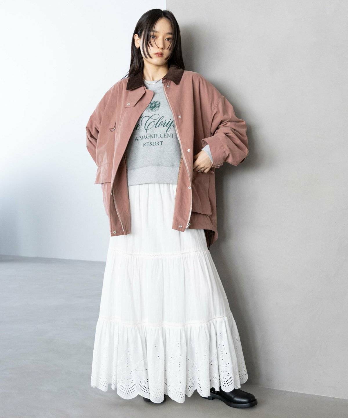 ピンクのブルゾンに白スカートを合わせた女性