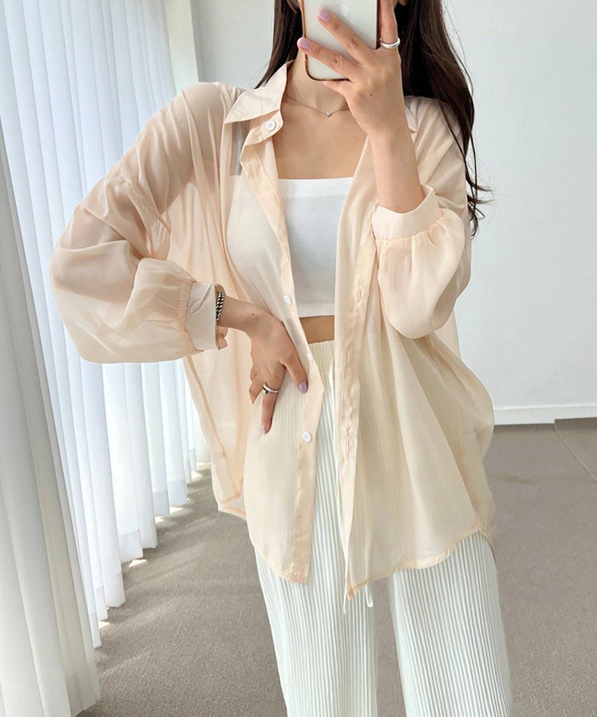 ベージュのシャツに白パンツを合わせた女性