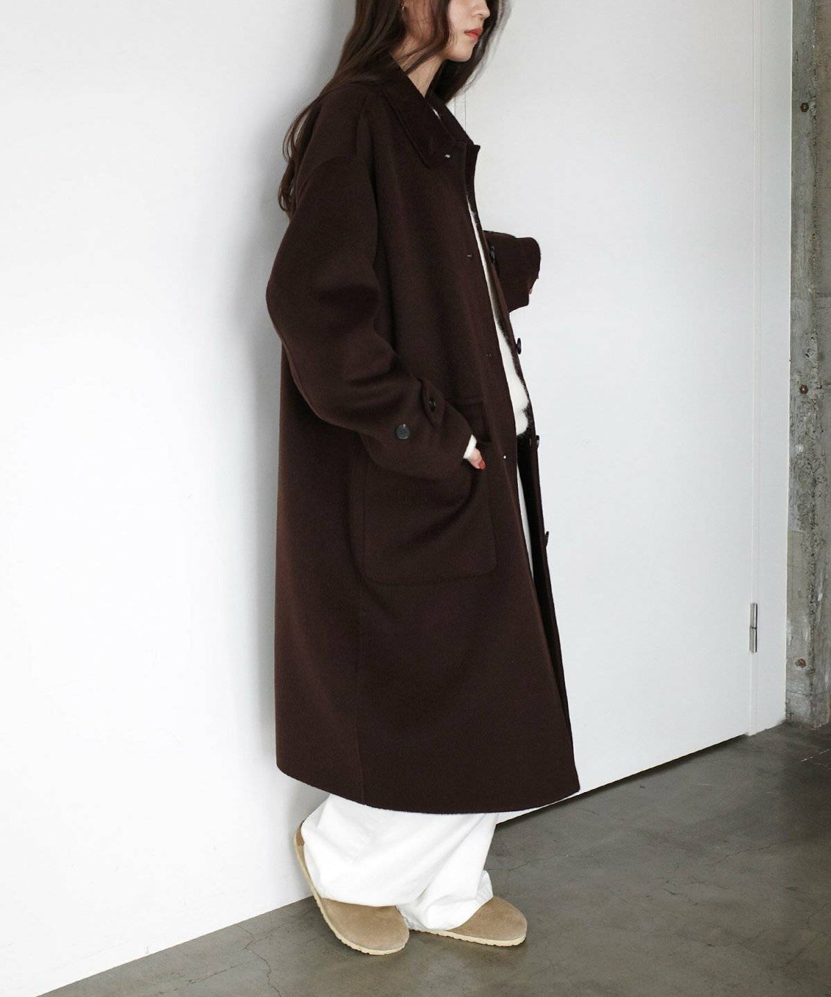 ホワイトコーデにブラウンのコートを羽織った女性