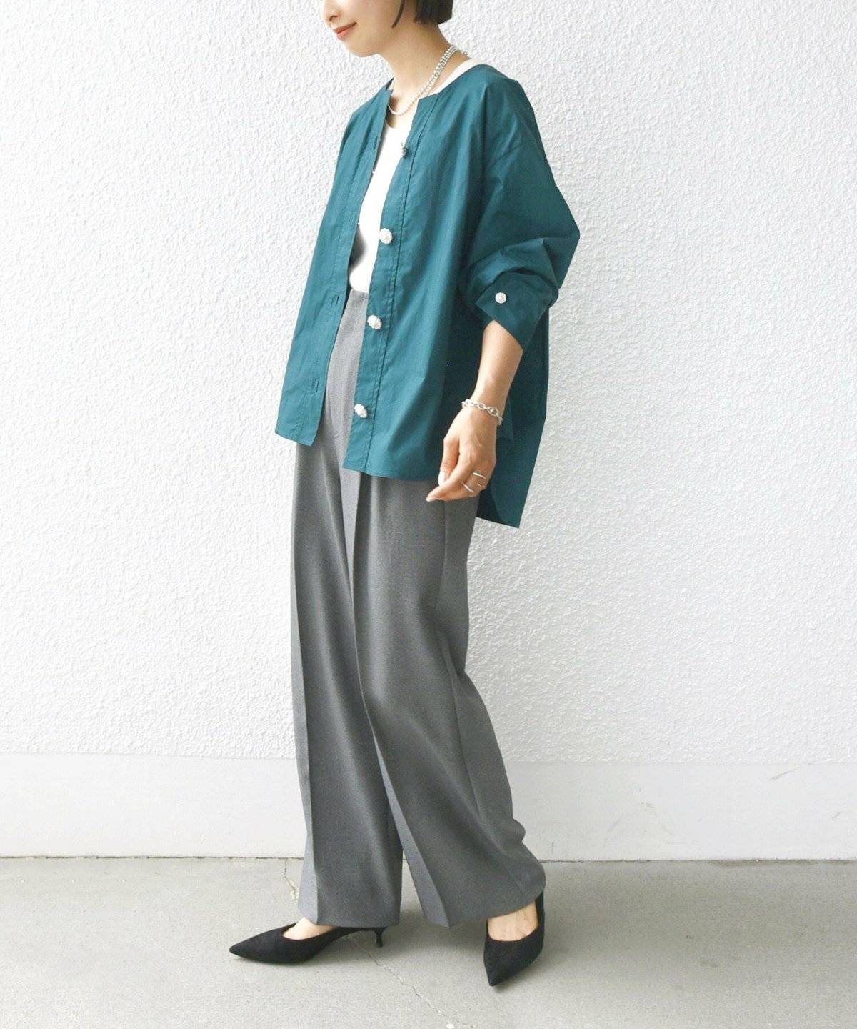 白Tシャツにパンツを合わせてグリーンのロングシャツを羽織った女性