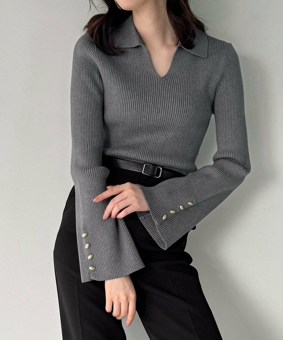 グレーのニットに黒パンツを合わせた女性