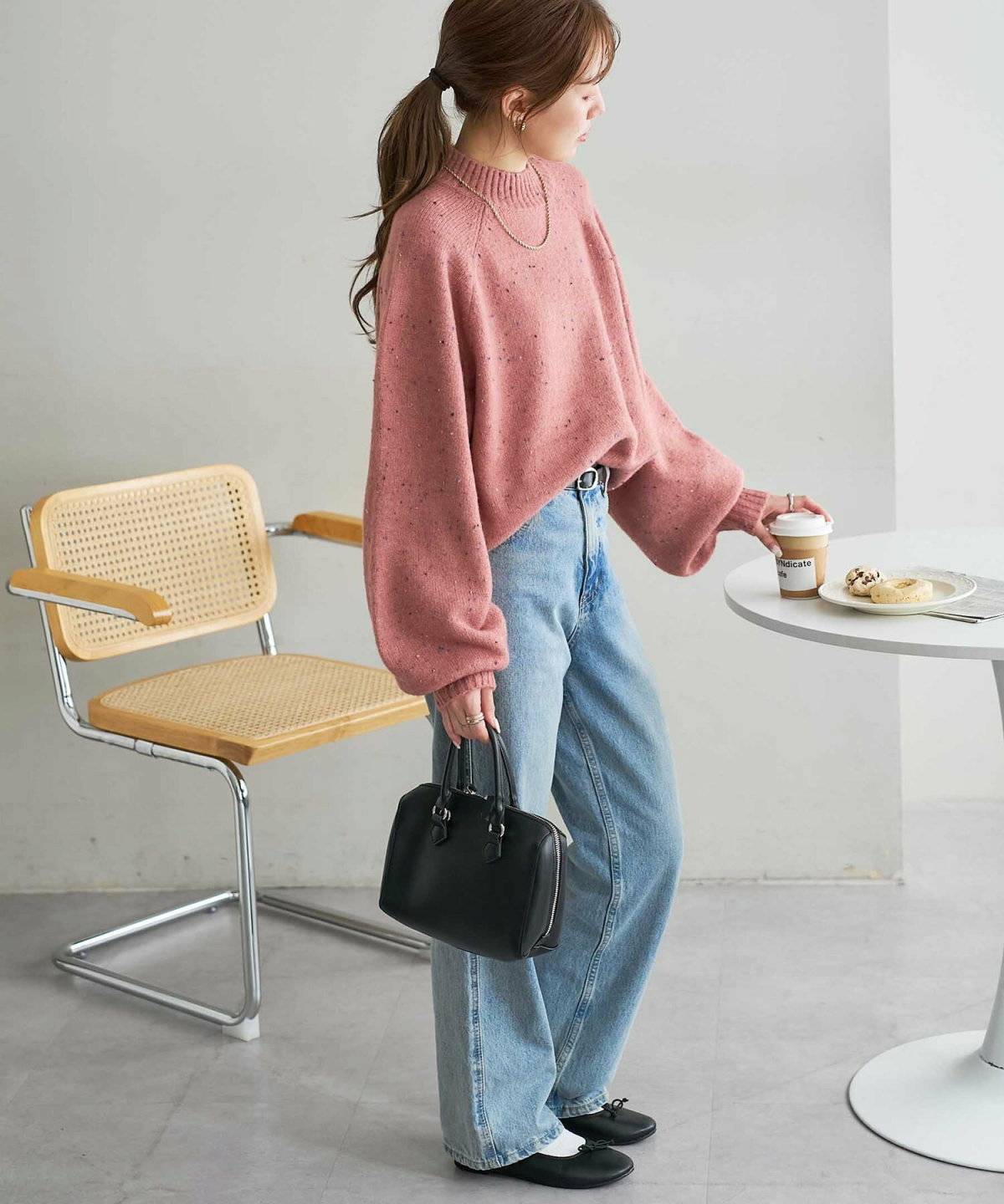 ピンクのカラーニットにデニムを合わせた女性