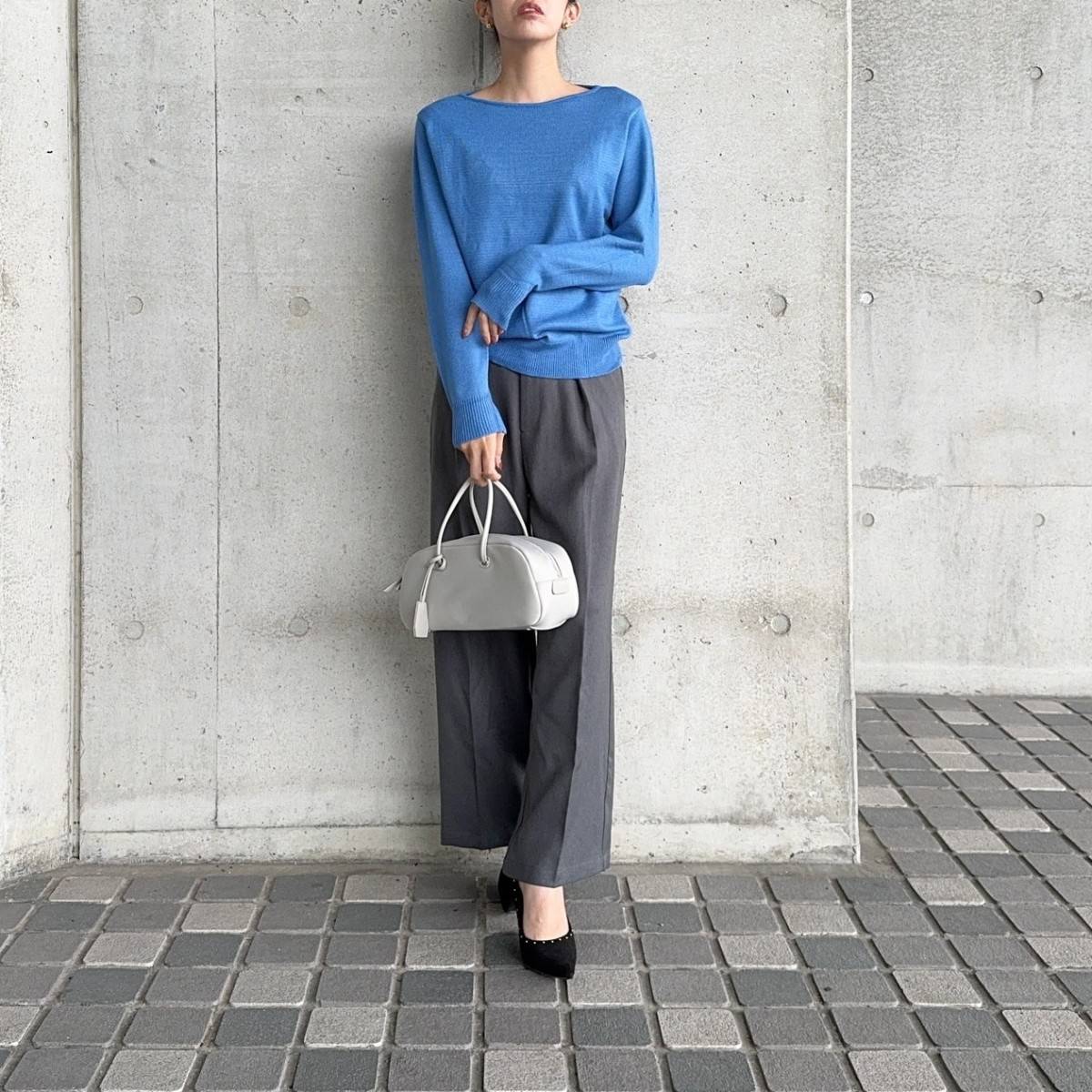 ブルーのニットにグレーのパンツを合わせた女性