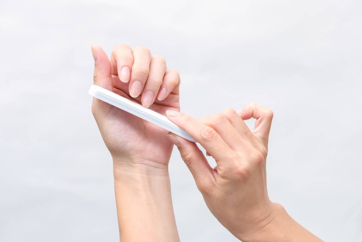 爪やすりで爪を削ってネイルケアを行う女性