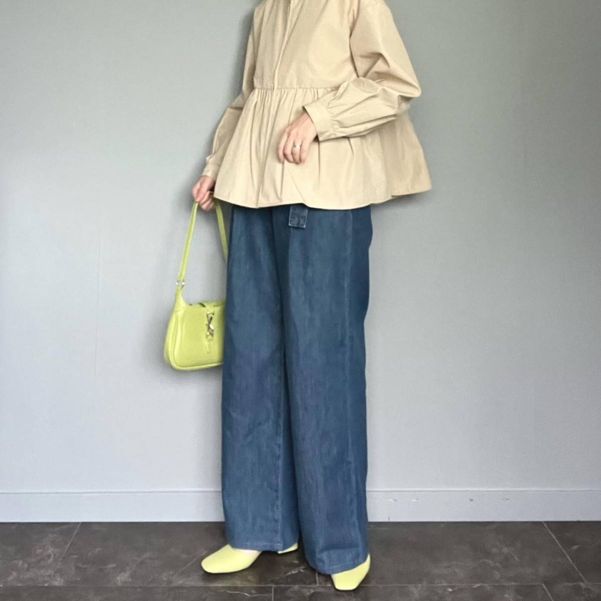 ベージュのブラウスにデニムパンツを合わせた女性