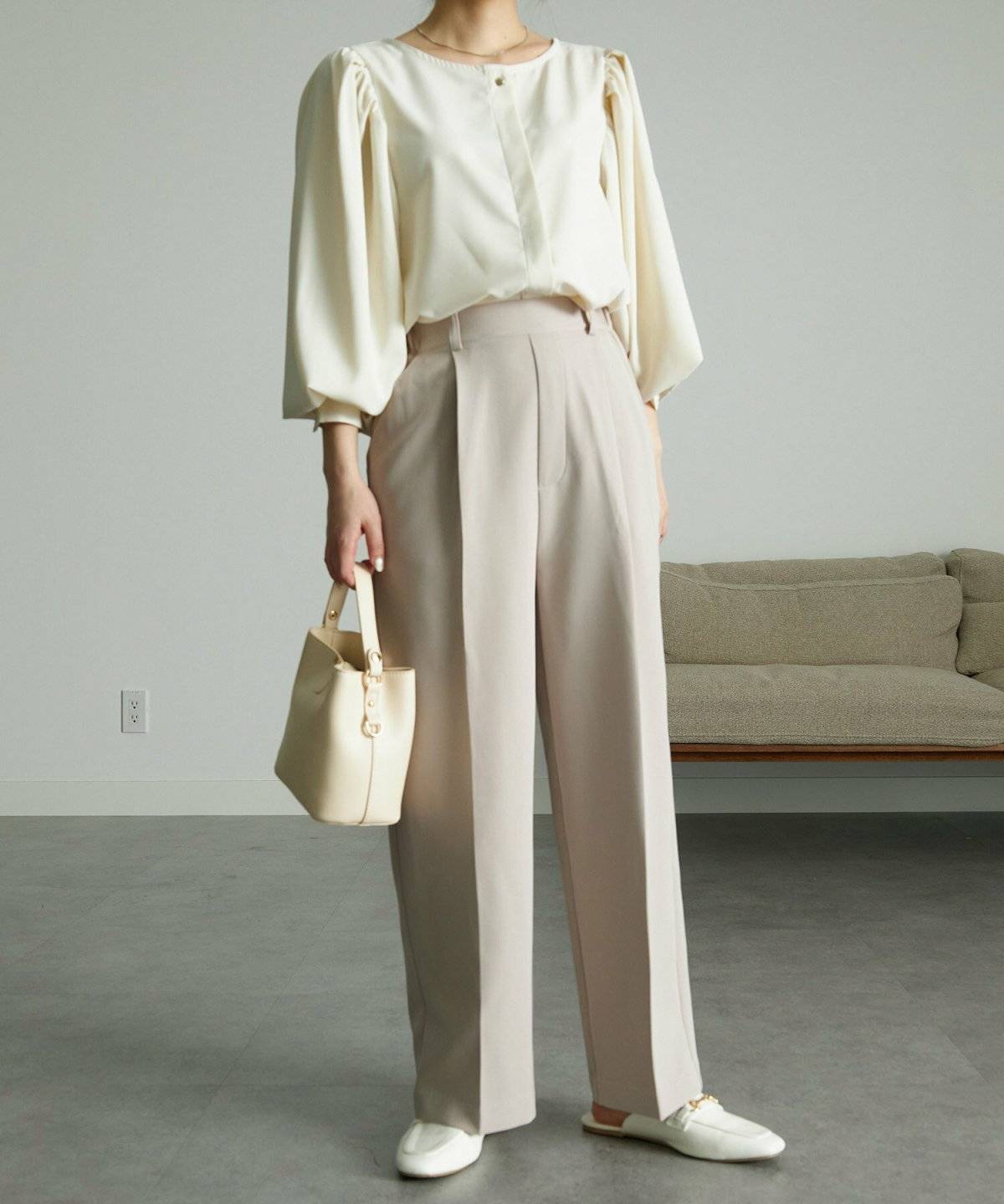 白トップスにベージュのパンツを合わせた女性