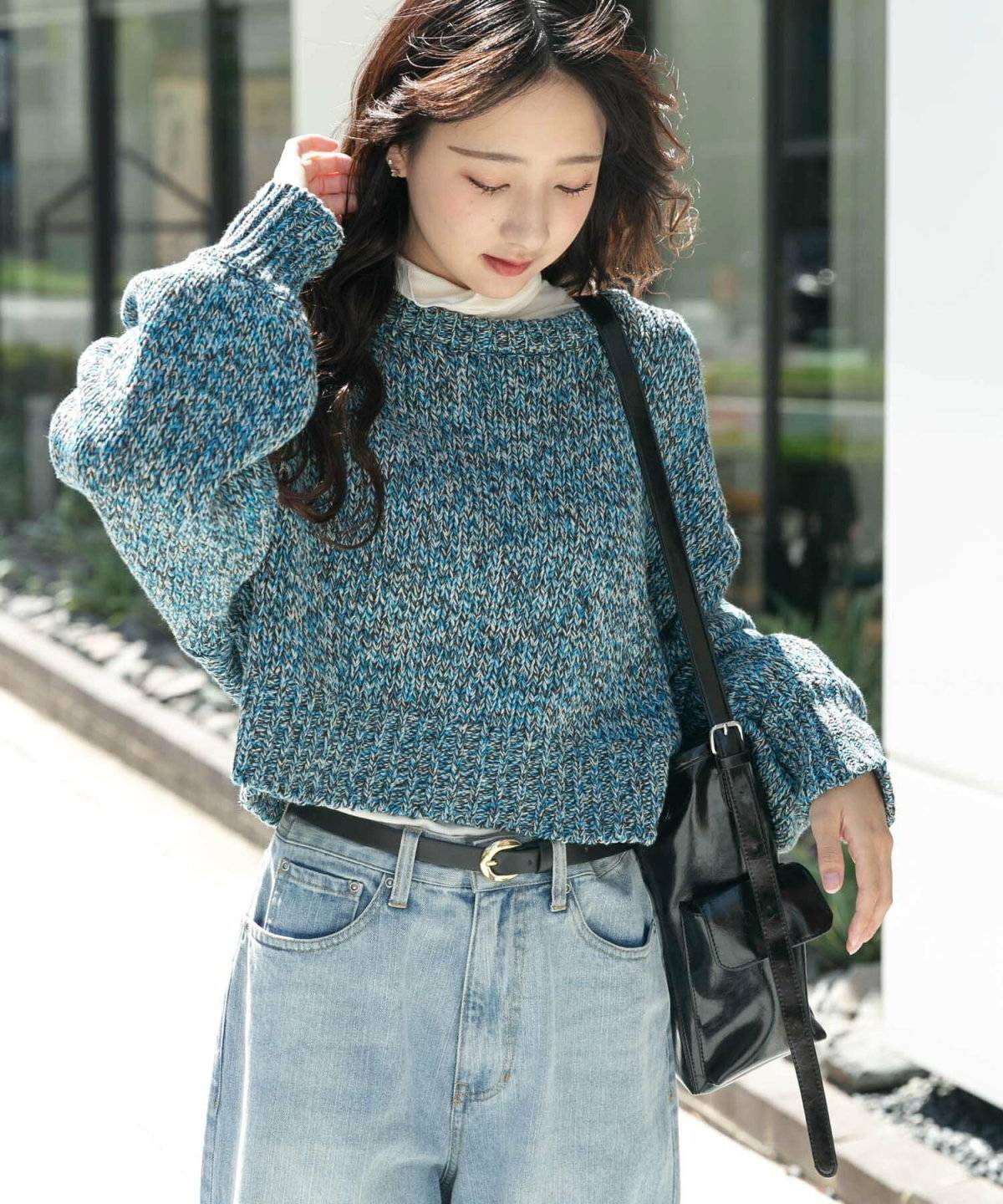 グリーンのニットにデニムを合わせた女性