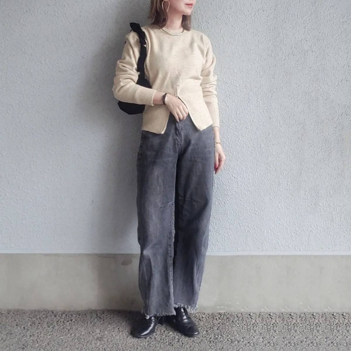 ベージュのニットにデニムパンツを合わせた女性