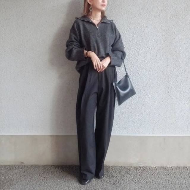グレーのニットに黒パンツを合わせた女性
