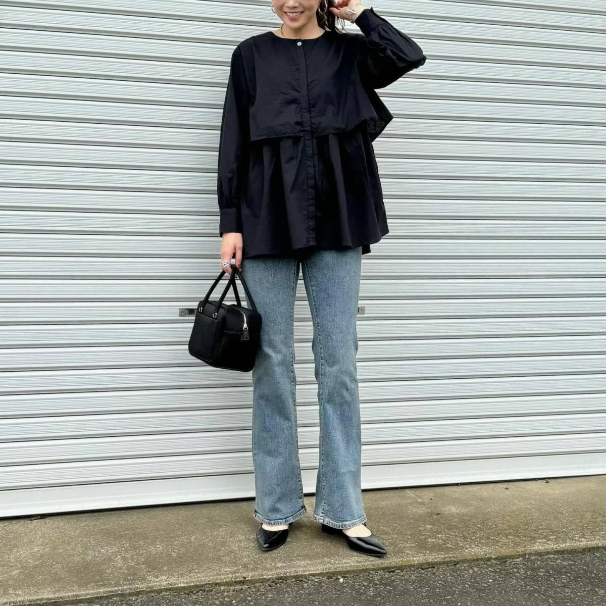 黒ブラウスにデニムパンツを合わせた女性