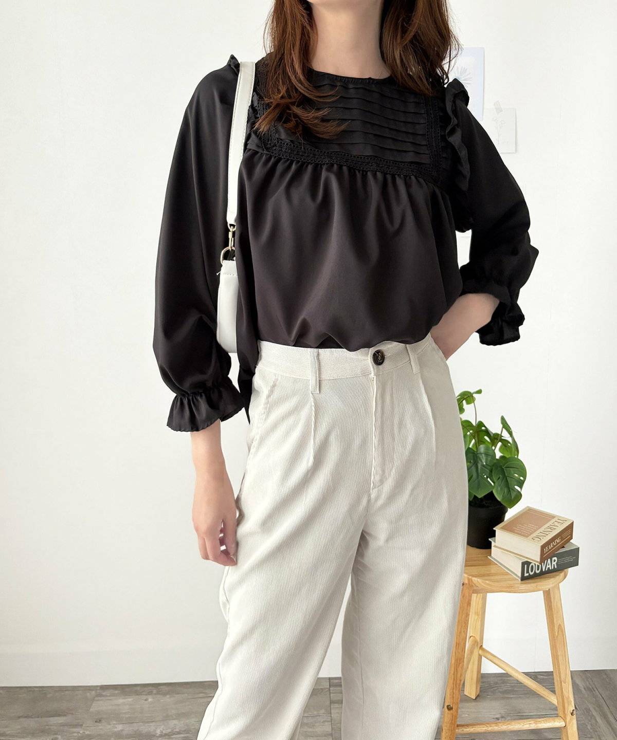 レースブラウスにベージュのワイドパンツを合わせた女性