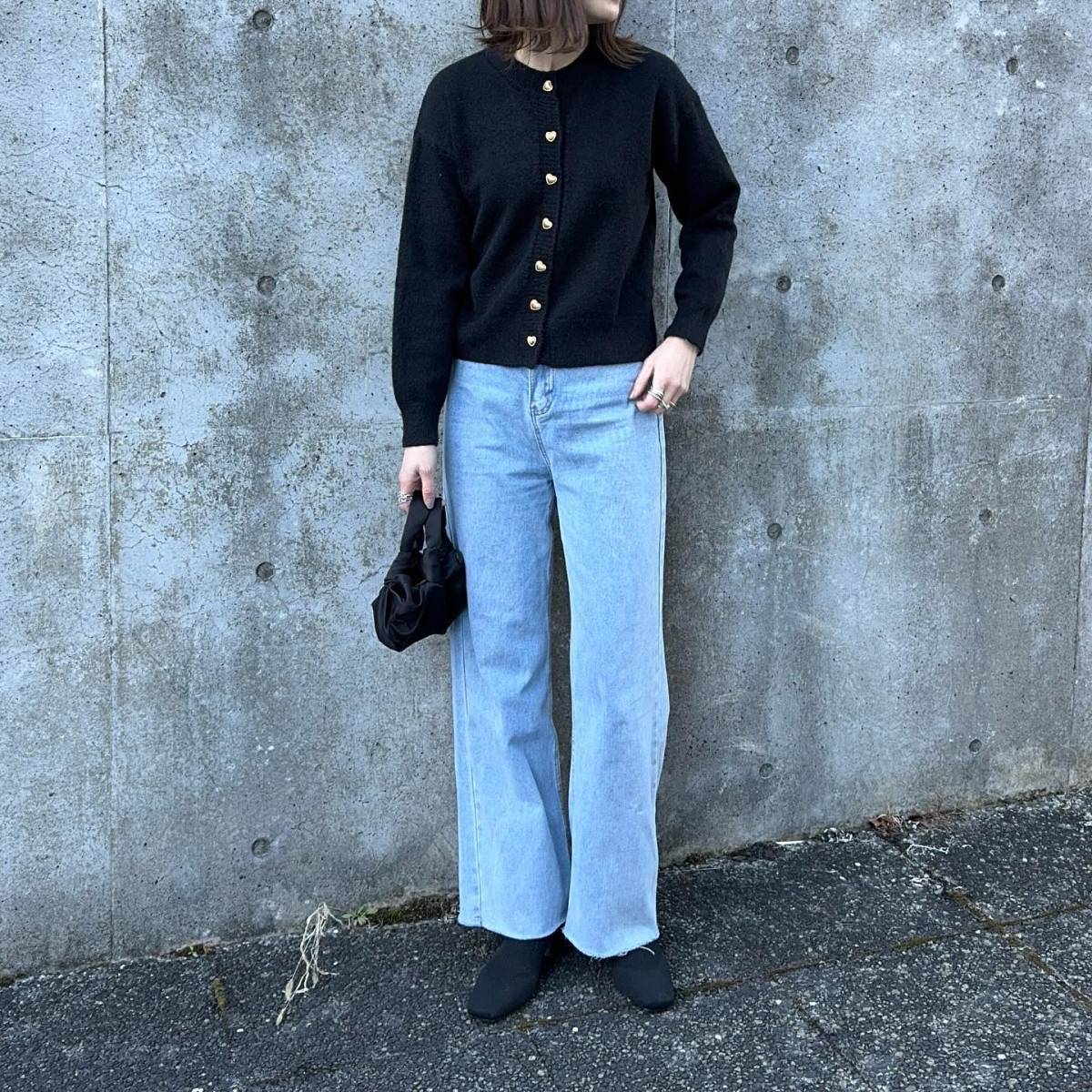 黒カーディガンにデニムパンツを合わせた女性