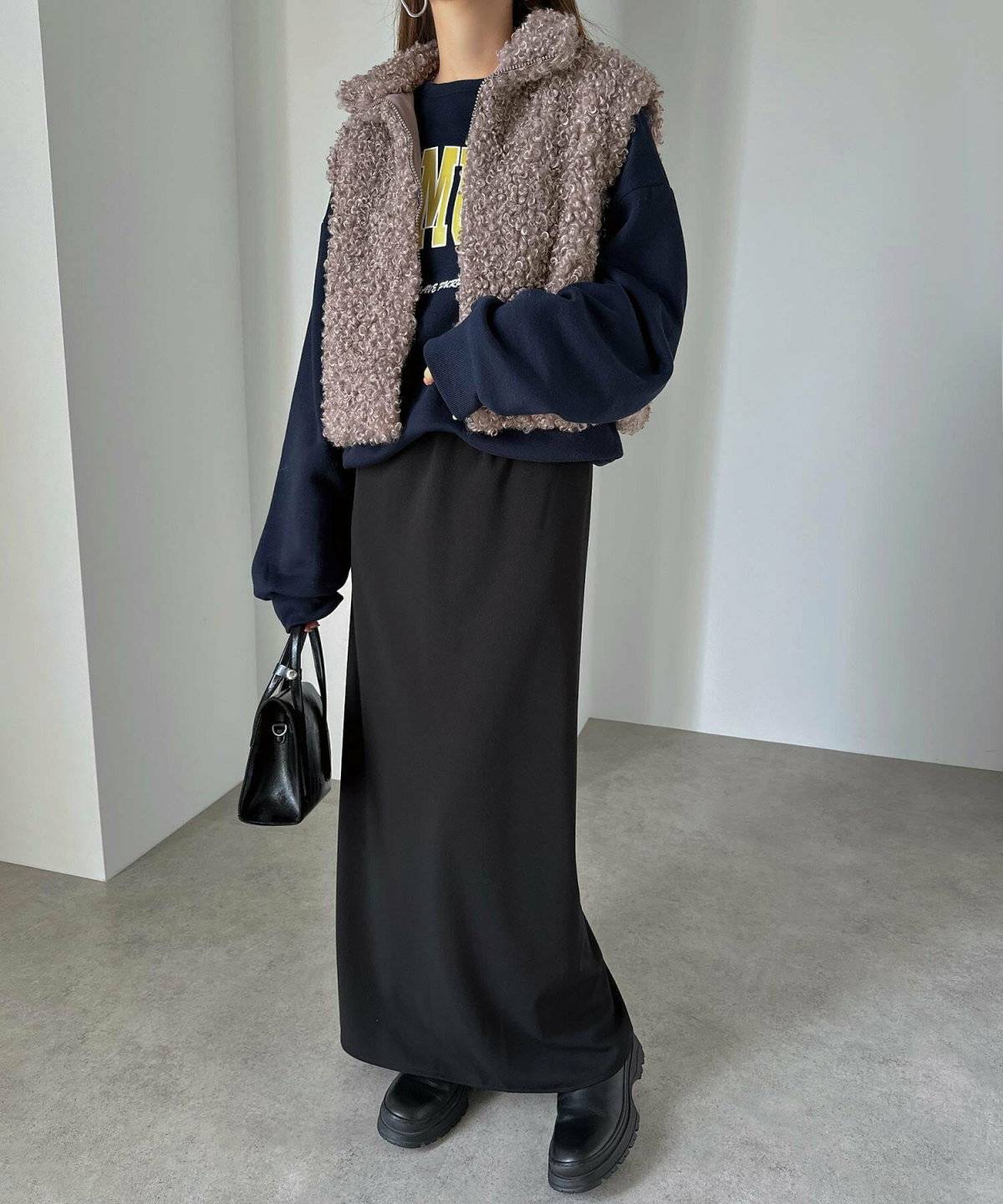 モノトーンコーデにブラウンのファーベストを重ねた女性