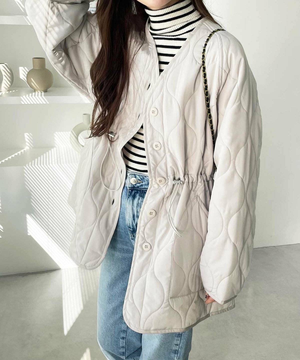 ボーダー柄トップスに白のキルティングコートを羽織った女性