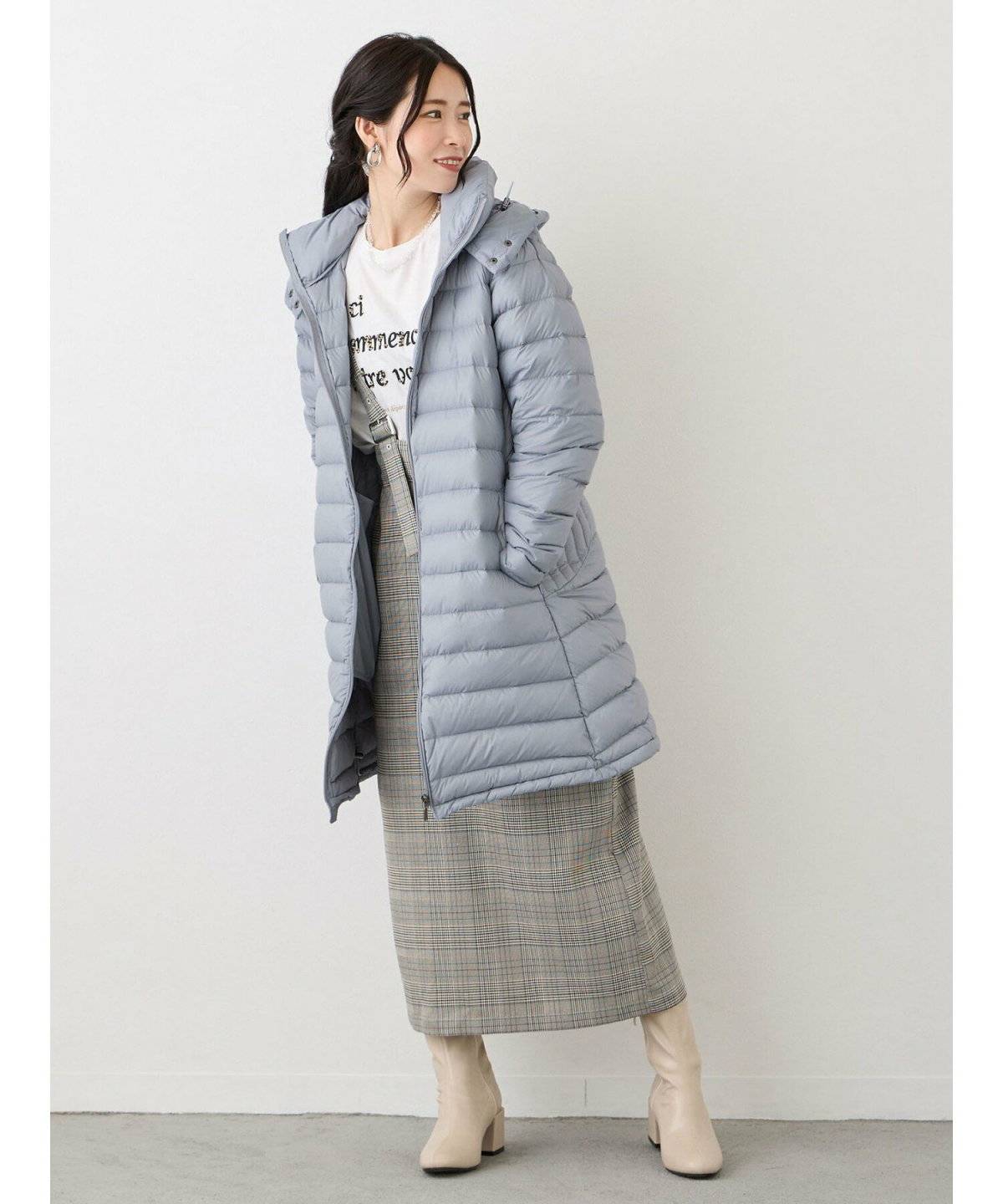 ブルーのダウンにグレーのスカートを合わせた女性