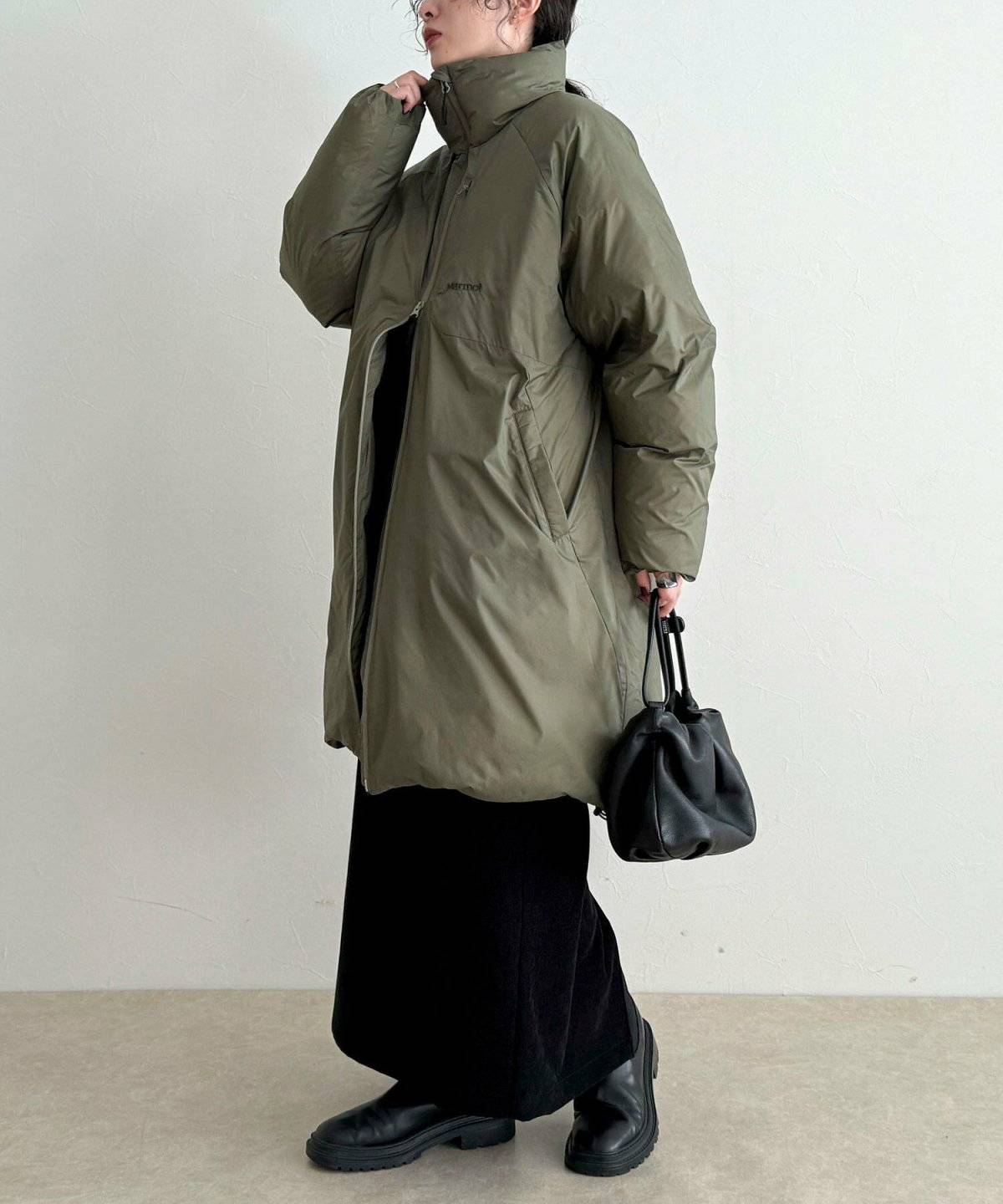 グリーンのダウンに黒のスカートを合わせた女性